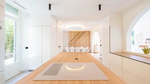 A modern kitchen with a central island, a dining area with white chairs, and a staircase leading to another level. - 008 Villa Rosoliel in Cannes (Cannes)