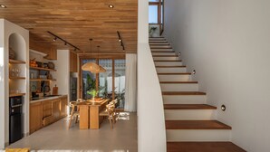A modern interior with a wooden staircase, a kitchen with wooden cabinets, and a dining area with a table and chairs.