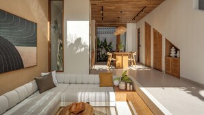 A modern interior with a white sofa, wooden ceiling, and a dining area with a table and chairs.