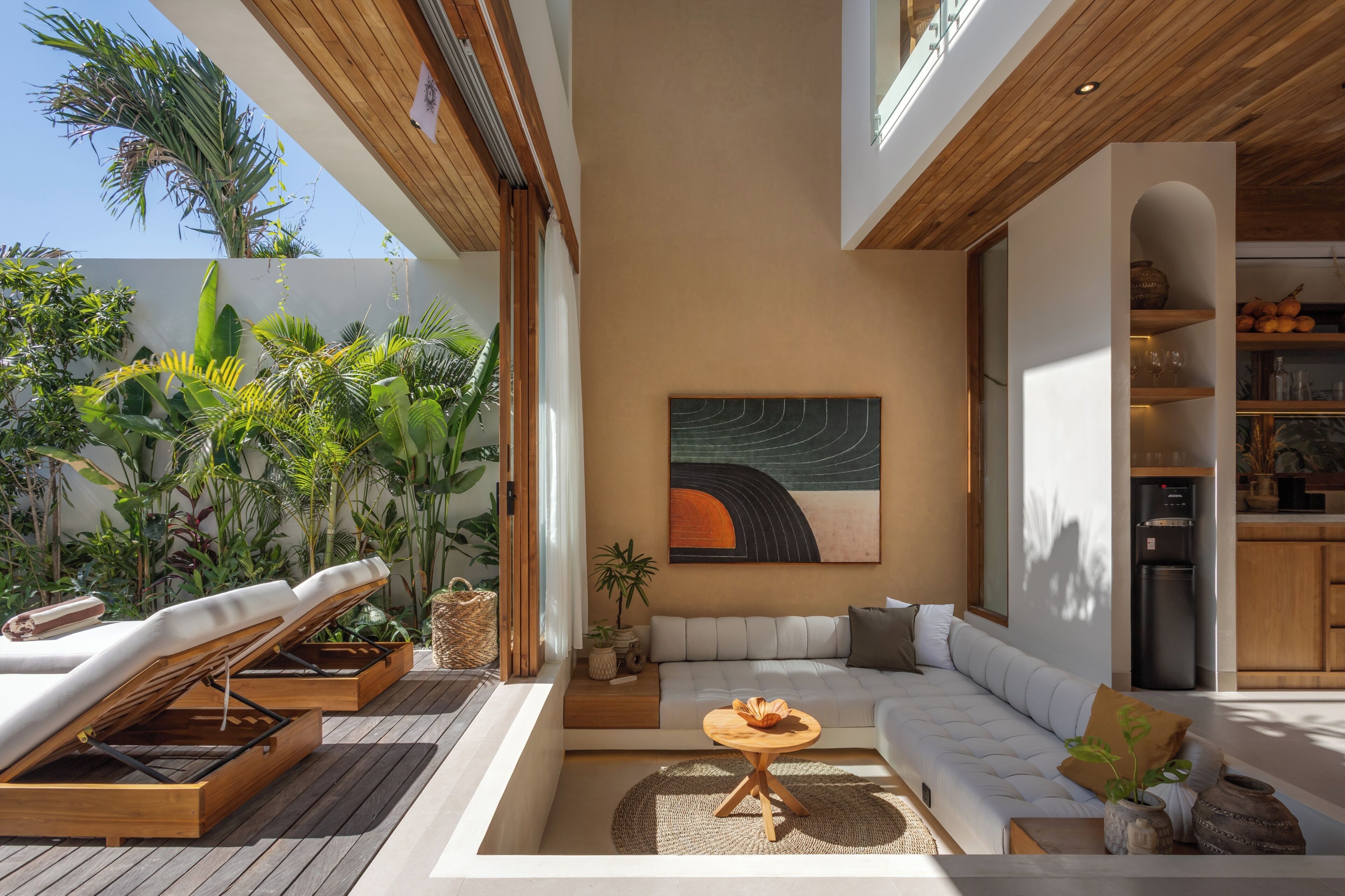 A modern living area with a wooden ceiling, a sofa, a table, and a painting.