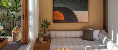 A modern interior with a white sofa, a round wooden table, and a large abstract painting on the wall.