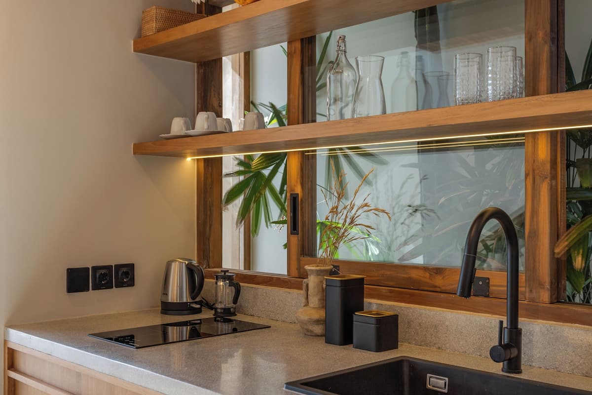A modern kitchen with wooden cabinetry, a black sink, and a window above the countertop.