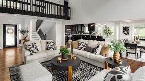 Un'ampia zona giorno con soffitto alto, una scala, una cucina e un'area pranzo.