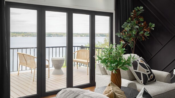 Ein Zimmer mit Seeblick, einem Balkon mit Korbmöbeln und einem Blumentopf.