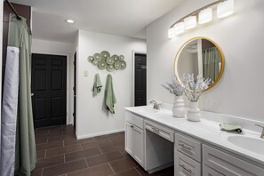 A bathroom with a white vanity, a round mirror, and a shower curtain.