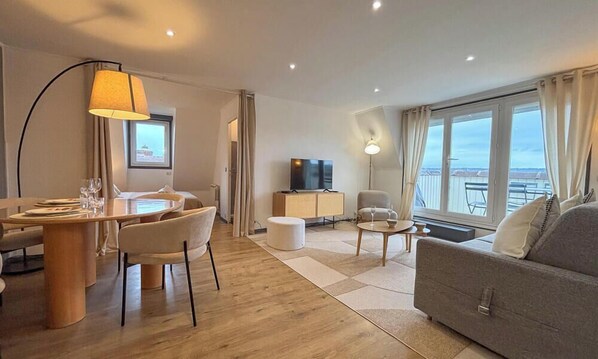 A modern living room with a dining area, a TV, and a sofa. - L'Horizon - Appartment Bénerville sur Mer - 4 people - Balcony and parking lot (Benerville-sur-Mer)