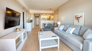 Ein modernes Wohnzimmer mit einem grauen Sofa, einem weißen Couchtisch und einem Fernseher auf einer weißen Konsole.