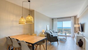Ein modernes Wohnzimmer mit einem Holzesstisch, Stühlen, einer Couch und einem Fernseher.