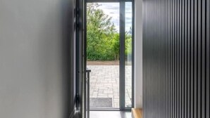 A modern interior with a glass door leading to an outdoor area, a bench, and a vertical panel on the right. - Villa Aurora mit Sauna und Whirlpool (Dranske)