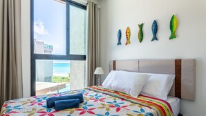 A hotel room with a bed, a view of the ocean, and a wall with fish decorations. - FlatCarneiros-Varanda com Vista-SH152 (Tamandaré)