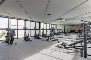 Ein modernes Fitnessstudio mit vielfältigen Trainingsgeräten, großen Fenstern und einem hellen, geräumigen Ambiente.