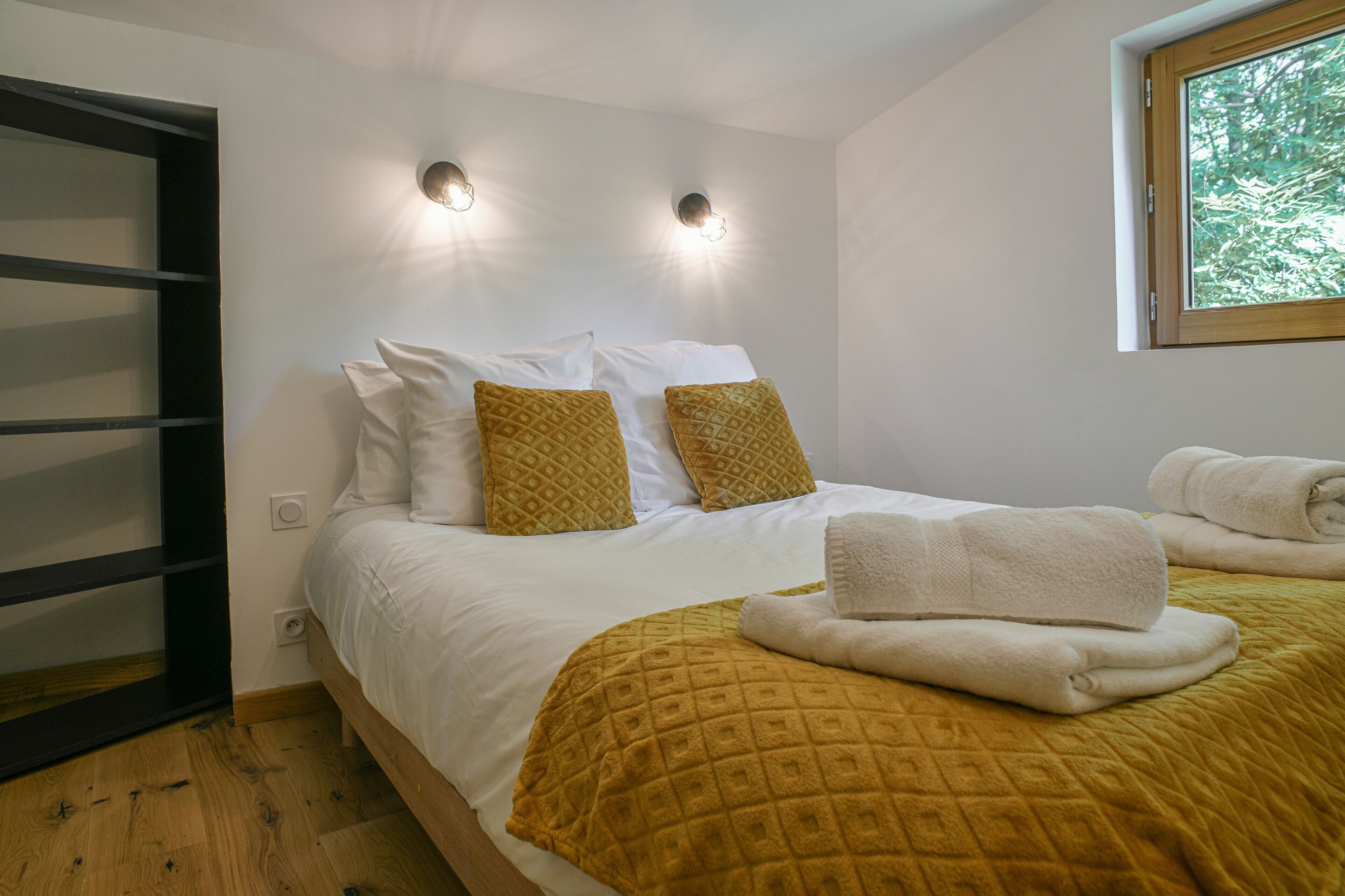 Ein Schlafzimmer mit einem Bett, zwei Wandleuchten, einem Fenster und Holzboden.