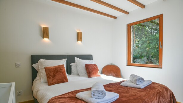 A bedroom with a bed, pillows, a window, and a towel on the bed. - Spacious House with Garden & Gym – Porte de Savoie (Porte-de-Savoie)