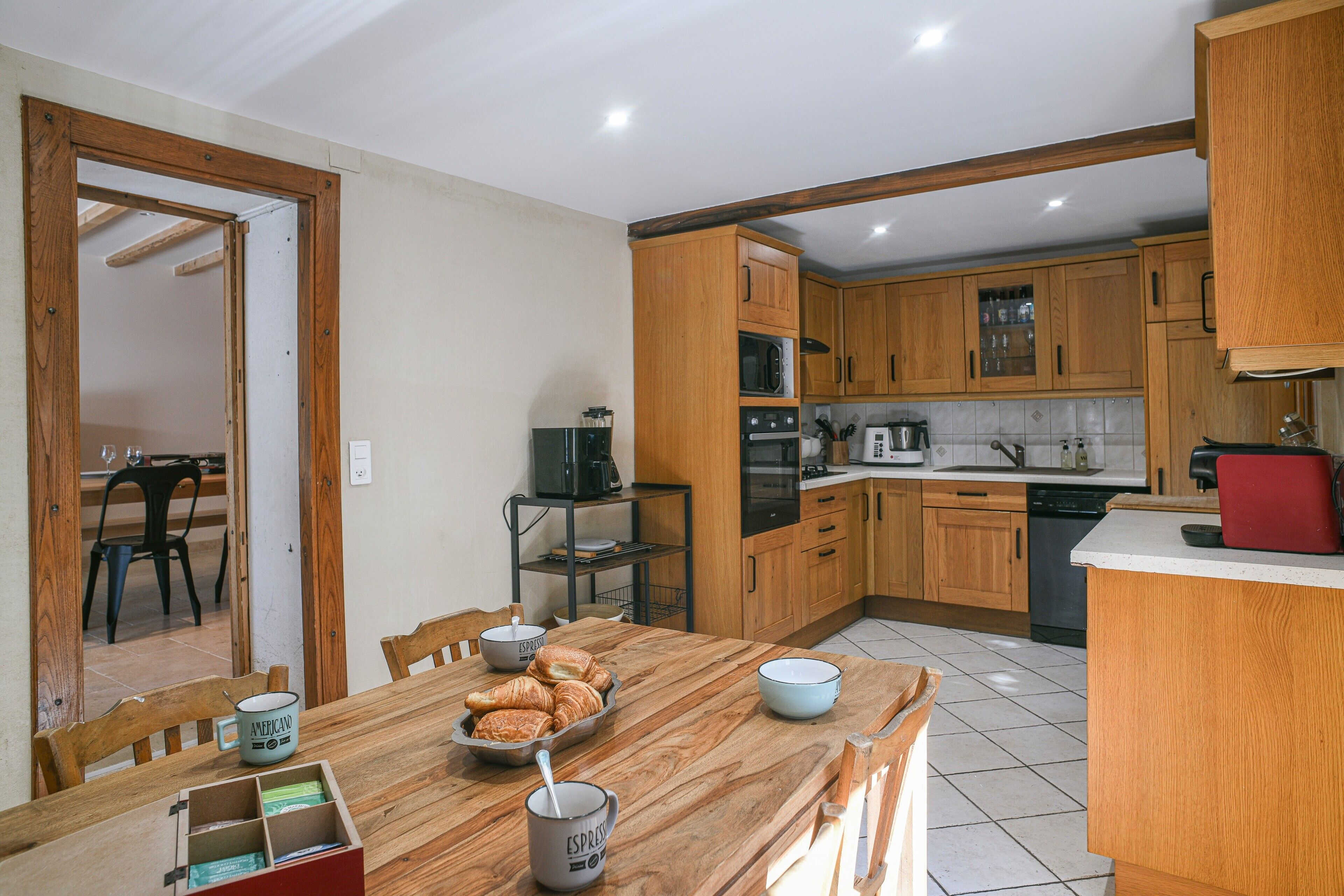 Una cocina con armarios de madera, una mesa de comedor con sillas y una zona para desayunar.