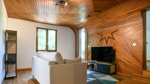 A modern living room with a sofa, TV, wooden walls, and a star-shaped design on the wall. - Spacious House with Garden & Gym – Porte de Savoie (Porte-de-Savoie)