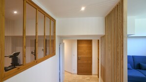 A hallway with a wooden-framed window, a door, and a blue sofa. - Spacious House with Garden & Gym – Porte de Savoie (Porte-de-Savoie)