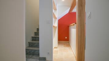 Eine Treppe führt zu einem Raum mit einer roten Akzentwand und einem hölzernen Türrahmen.