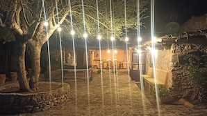Un patio de piedra con un banco de madera rústica, una lámpara colgante y un muro de piedra.