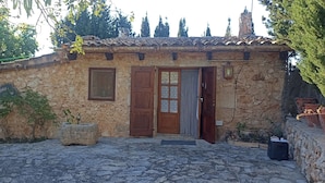 Un edificio de piedra con techo de tejas, puerta de madera y una ventana pequeña.