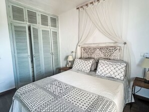A bedroom with a bed, a nightstand, a lamp, a wardrobe, and a canopy bed. - Traditionelles Haus El Vaixell - Terrassen mit Aussicht by Interhome (San José Ibiza)