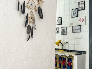 Eine Wand mit Traumfängern und gerahmten Fotos, eine gelbe Schreibtischlampe und ein gemustertes Vorhang.