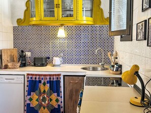 Eine Küche mit gelben Schränken, einer Kaffeemaschine, einem Toaster und einem Spülbecken.