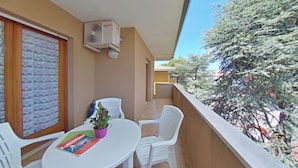 Ein Balkon mit Tisch, Stühlen, einem Blumentopf und einer Klimaanlage.