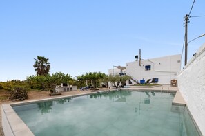 A swimming pool with lounge chairs, a staircase, and a building with a white facade.