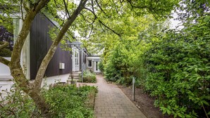 A pathway leading to a building surrounded by lush greenery and trees.