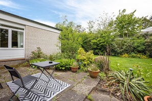 A patio with a table and chairs, surrounded by potted plants and a grassy area. - Apartment Kleine Seeperle in Quickborn – Quiet, Modern, and Well Connected (Quickborn)