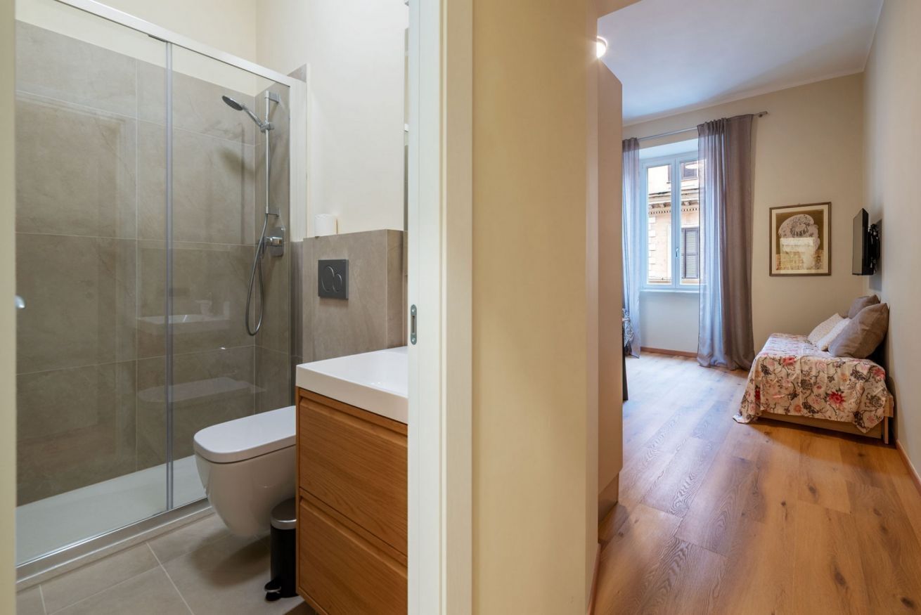Een badkamer met een douchecabine van glas, een toilet en een houten wastafelmeubel.