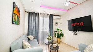 Ein modernes Wohnzimmer mit einer Couch, einem Couchtisch, einem Fernseher und einer Topfpflanze.