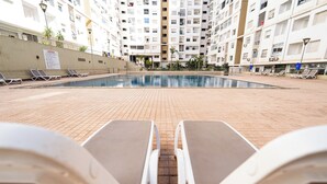 Ein Swimmingpool mit Liegestühlen und einem Hochhaus im Hintergrund.