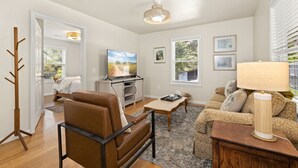 A living room with a brown leather sofa, a wooden coffee table, a TV, and a lamp. - Cozy, Quiet 2 Bedroom with Hot Tub, Fire Pit, Close to Fayetteville (Winslow)