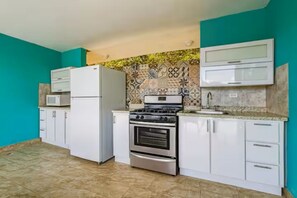 Eine Küche mit weißen Schränken, einem Herd, Backofen, einer Mikrowelle und einer Spritzschutzwand mit gemusterten Fliesen.