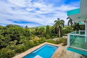 Ein modernes Haus mit Swimmingpool, üppigem Grün und blauem Himmel.