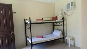 A bunk bed room with a door, a small stool, and an air conditioning unit. - Room-1 Person in 6 bed Dorm Mixed (Puerto Galera)