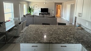 Eine moderne Küche mit weißen Schränken, einer Arbeitsplatte aus Granit und einem Essbereich mit einer Couch und Stühlen.