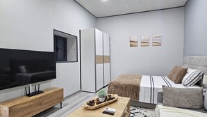 A modern bedroom with a TV, wardrobe, bed, and artwork. - Charming 1-bedroom Apartment With Ocean Views in Calheta (Calheta)