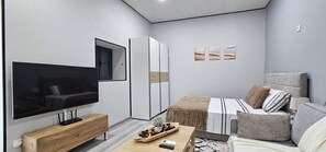 A modern bedroom with a TV, wardrobe, bed, and artwork. - Charming 1-bedroom Apartment With Ocean Views in Calheta (Calheta)