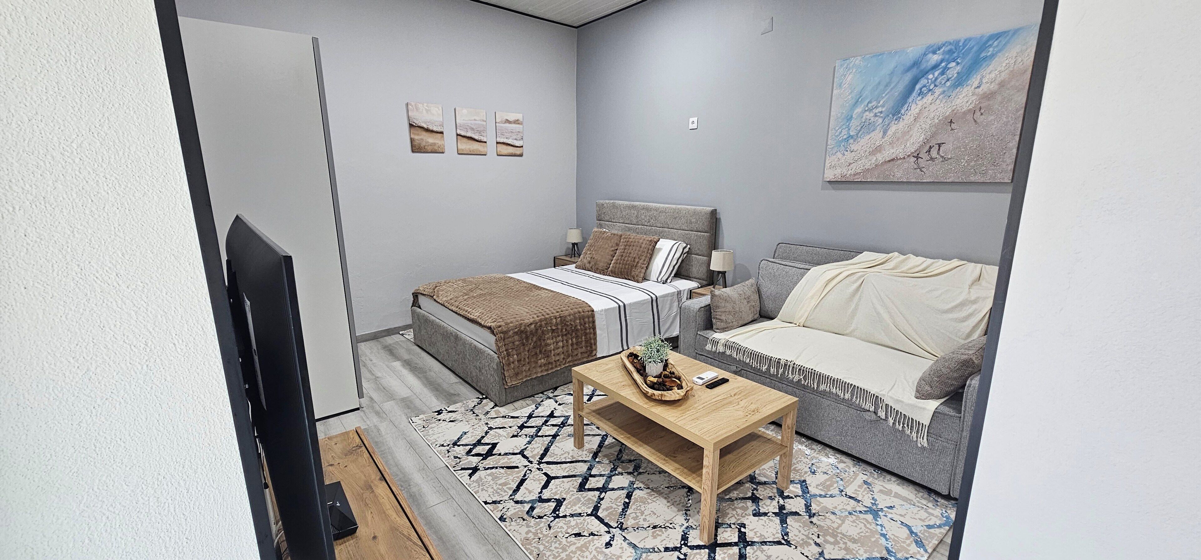 A modern bedroom with a bed, a sofa, a coffee table, and a painting on the wall.