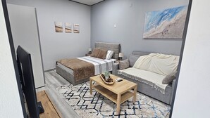 A modern bedroom with a bed, a sofa, a coffee table, and a painting on the wall. - Charming 1-bedroom Apartment With Ocean Views in Calheta (Calheta)