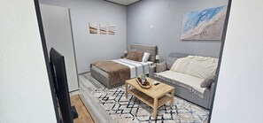 A modern bedroom with a bed, a sofa, a coffee table, and a painting on the wall. - Charming 1-bedroom Apartment With Ocean Views in Calheta (Calheta)