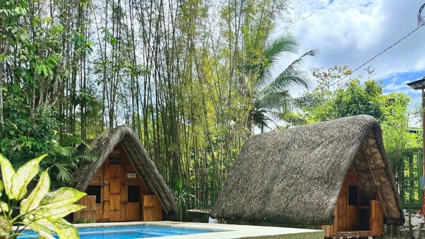 Two thatched-roof cabins with a pool in between. - Soulelle Villa (Silang)