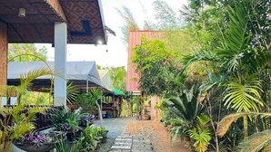 A pathway lined with potted plants leading to a building with a thatched roof. - Soulelle Villa (Silang)