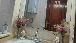 Casa de banho com um espelho grande, lavatório e flores decorativas.