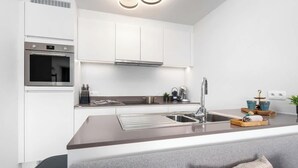 A modern kitchen with white cabinets, stainless steel appliances, and a central island with a sink. - La Dolce Vickri - modern stay with garden & pool (Nieuwpoort)