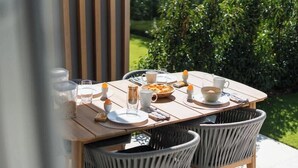 An outdoor dining table with chairs, plates, cups, and a bowl of food. - La Dolce Vickri - modern stay with garden & pool (Nieuwpoort)
