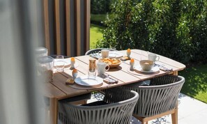 An outdoor dining table with chairs, plates, cups, and a bowl of food. - La Dolce Vickri - modern stay with garden & pool (Nieuwpoort)