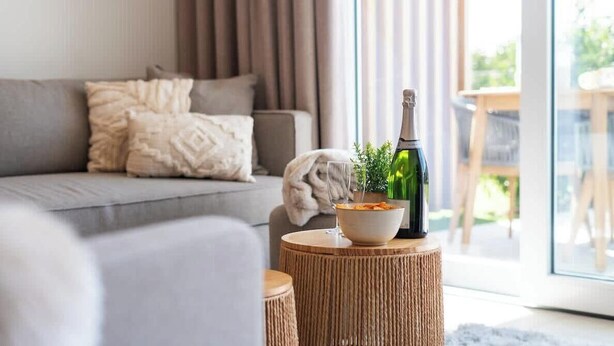 A modern living room with a sofa, a round wooden table, a bottle, and a bowl. - La Dolce Vickri - modern stay with garden & pool (Nieuwpoort)